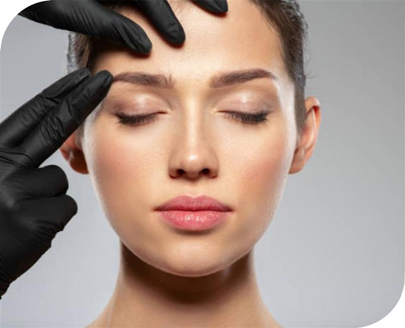 Gloved hands assessing brow position and symmetry before treatment